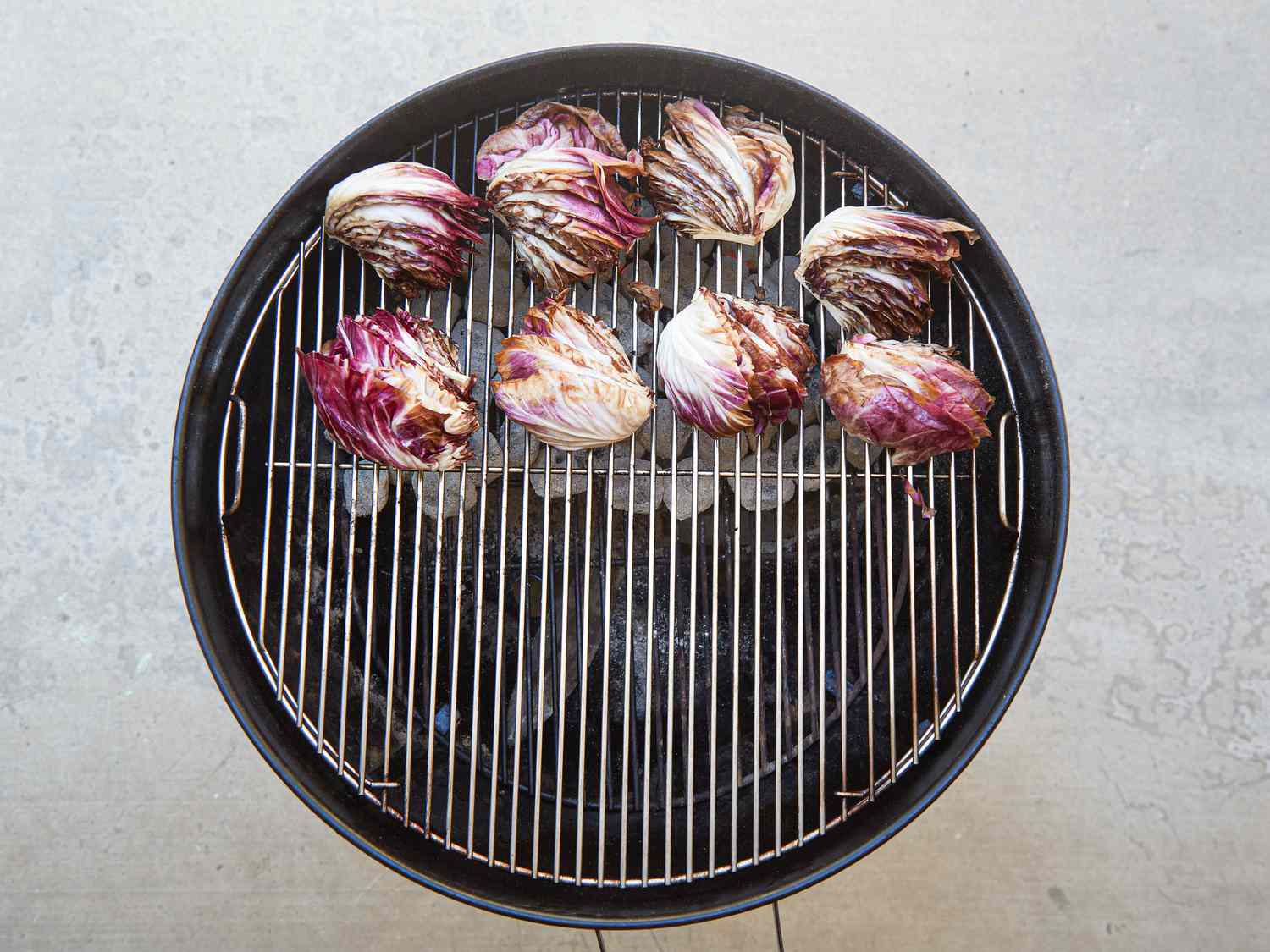 Grilled radicchio heads placed on an outdoor grill grate