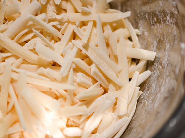 Closeup of grated cheeses coated with cornstarch.