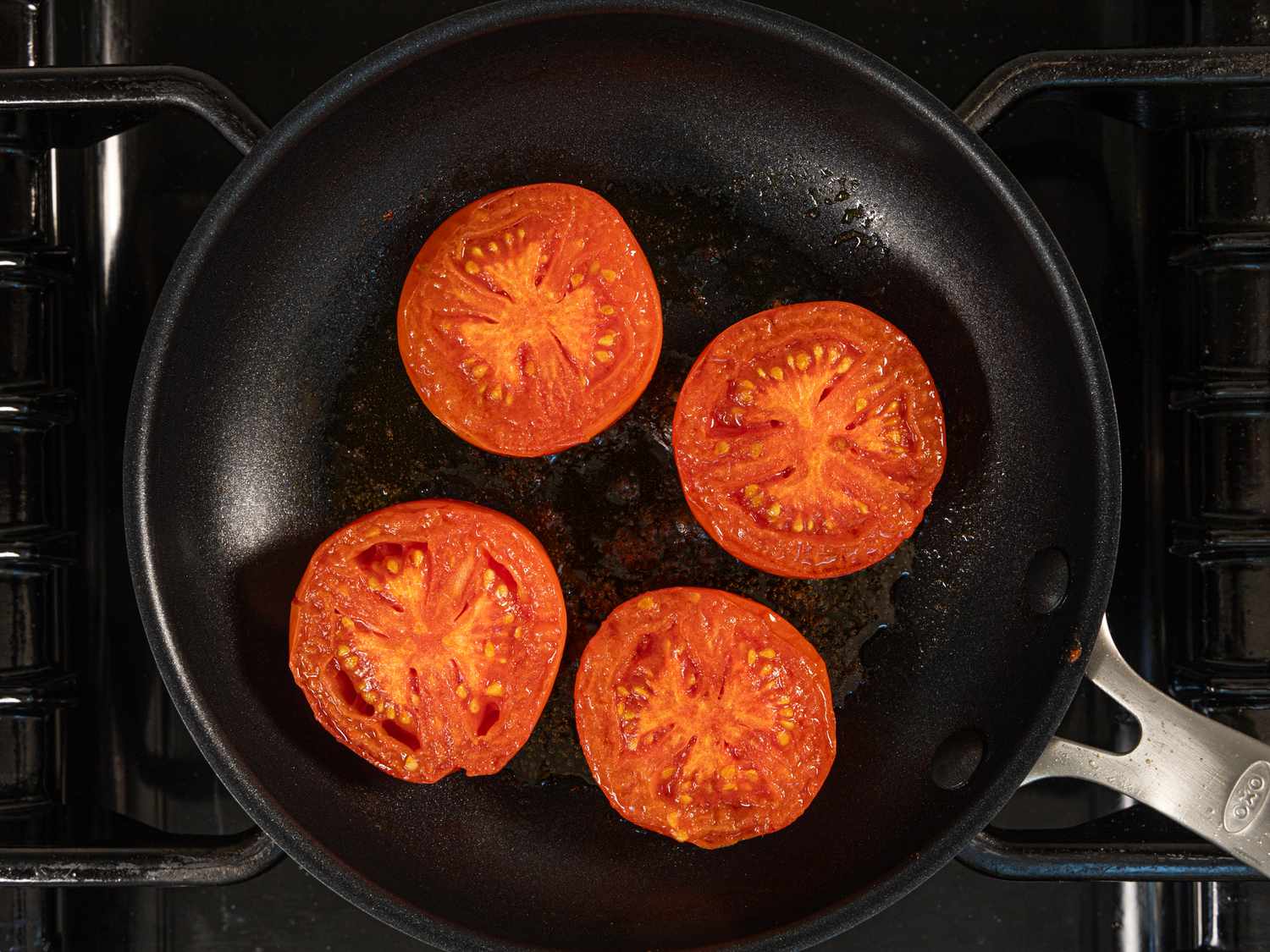 Overhead view of tomato slices cooking in pan