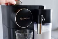 A person placing a pod in the Nespresso Gran Lattissima Original Espresso Machine by De’Longhi