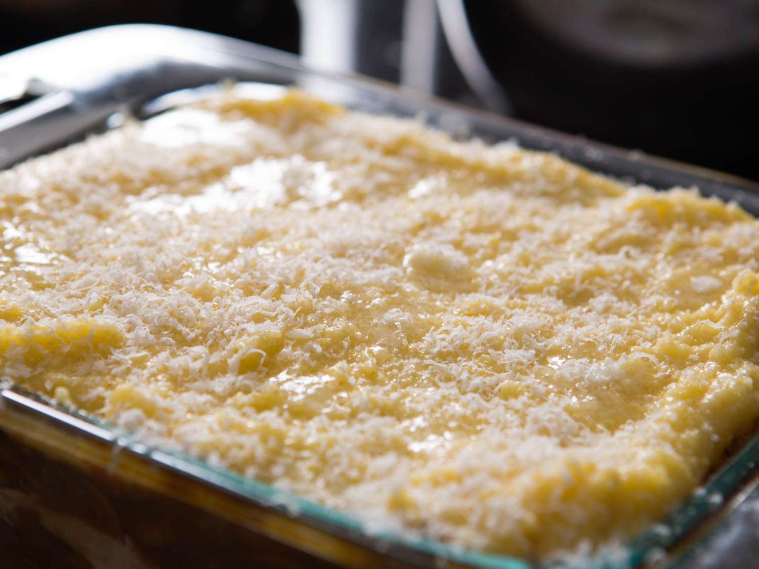 The assembled polenta lasagna, topped with butter and Parmesan cheese.