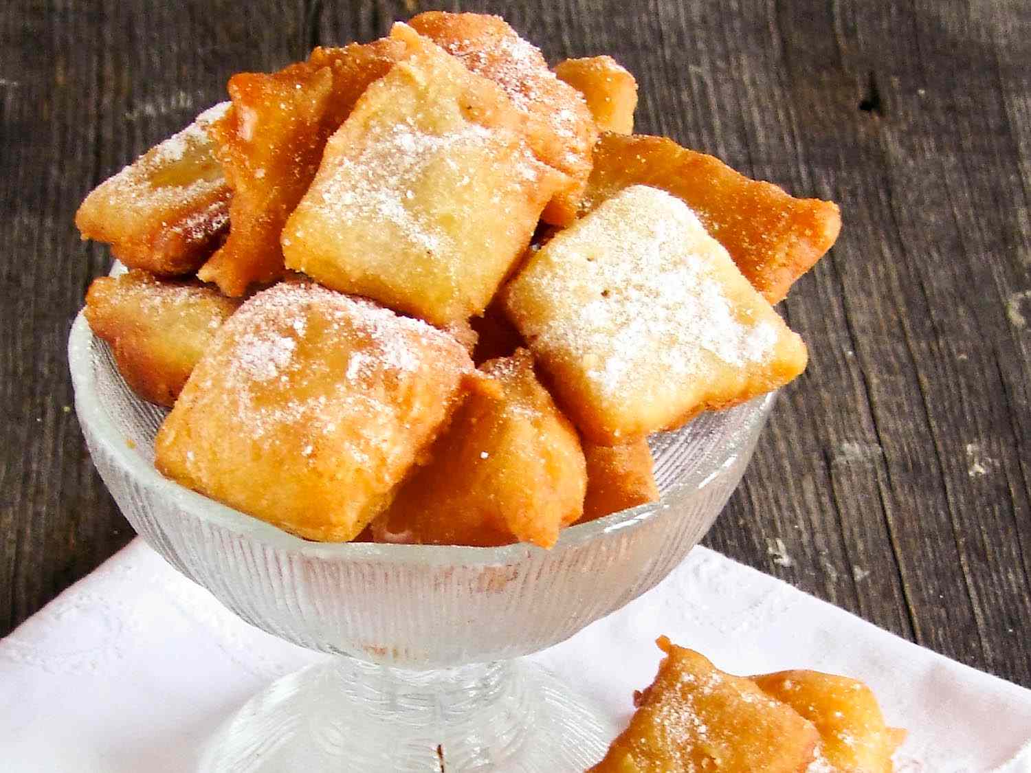 A bowl of pillowy tawa tawas in a glass dish, with a single one next to it.
