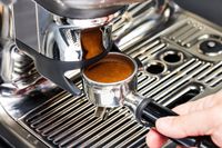 A person adjusting the portafilter onto the Breville Barista Touch Impress Espresso Machine with Grinder