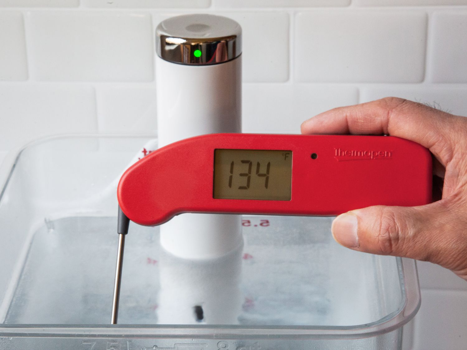 Hand using ThermoWorks Thermapen ONE to check the temperature of water