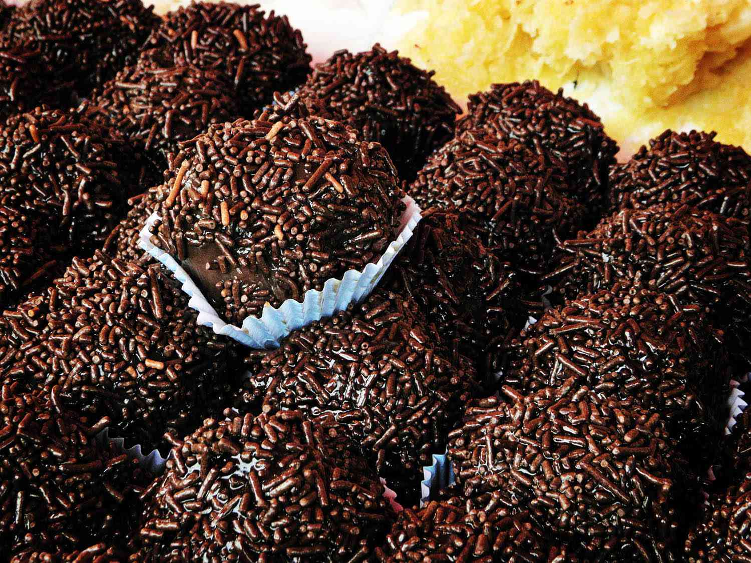 Several Brazilian brigadeiro, in small paper cups, covered in chocolate sprinkles.
