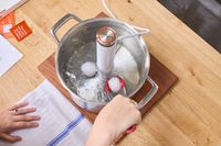 A person places eggs into a pot with the Breville Joule Turbo Sous Vide