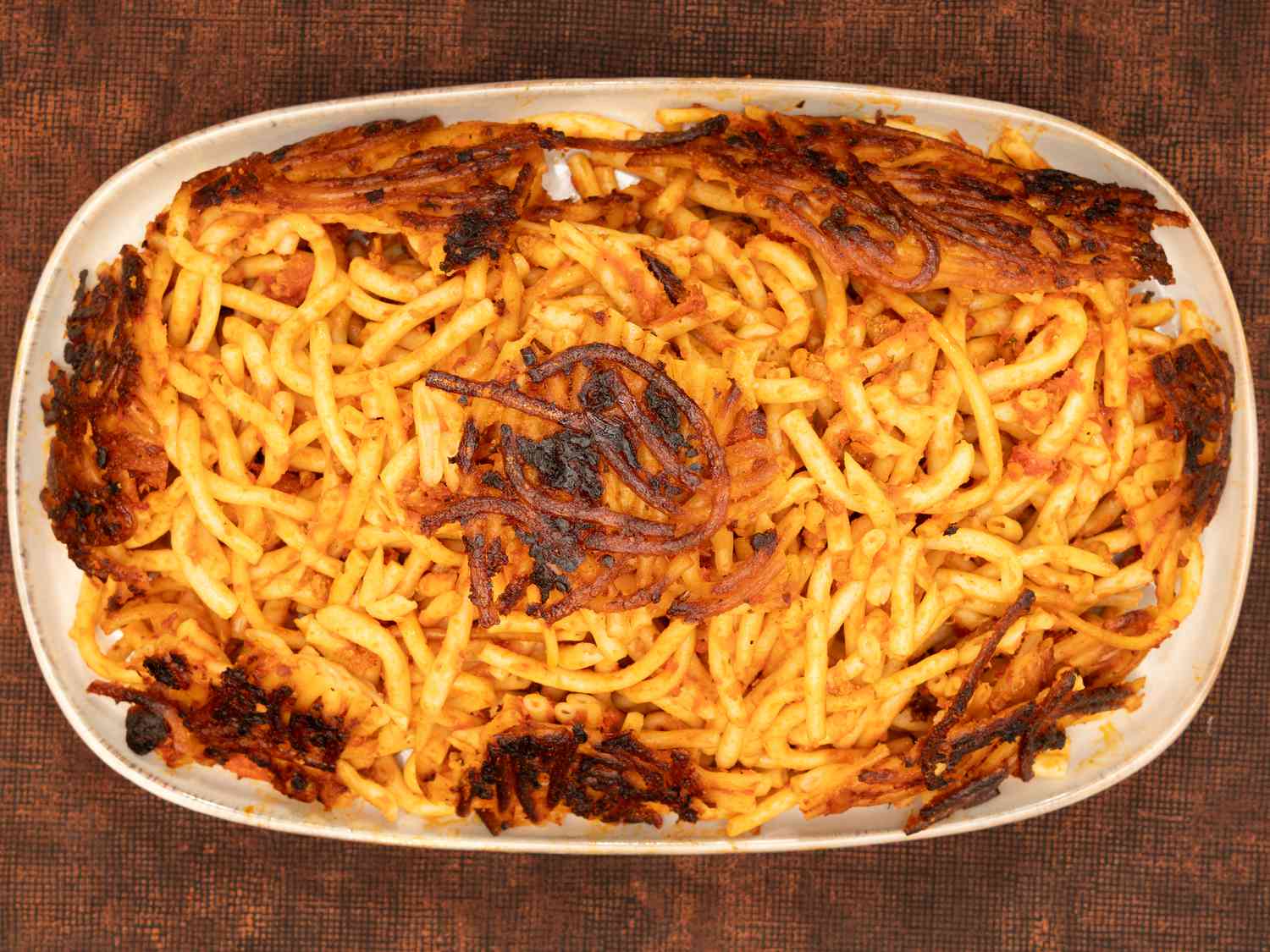 A dish of Tahdig macaroni with crispy edges, served in a white platter