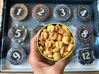 A person holding a tin of corn nuts on top of an Advent calendar