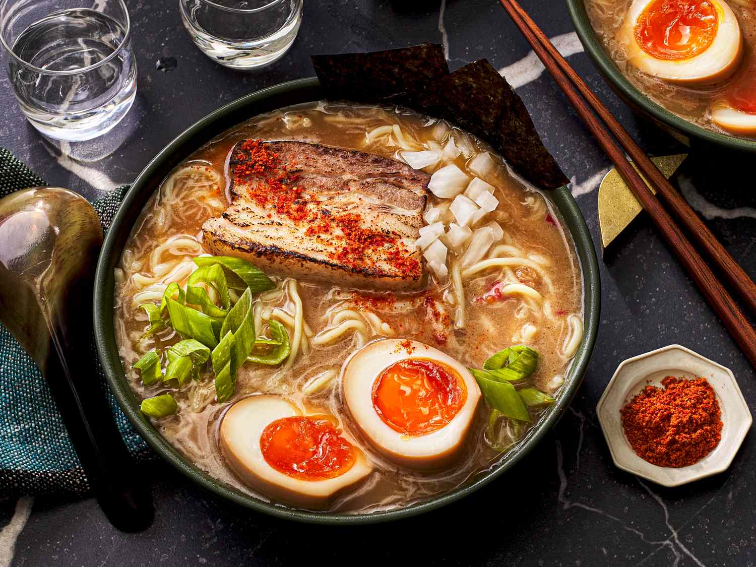 A bowl of ramen with pork softboiled eggs green onions and toppings