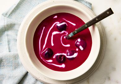 A bowl of beet and cherry soup with a swirl of sour cream
