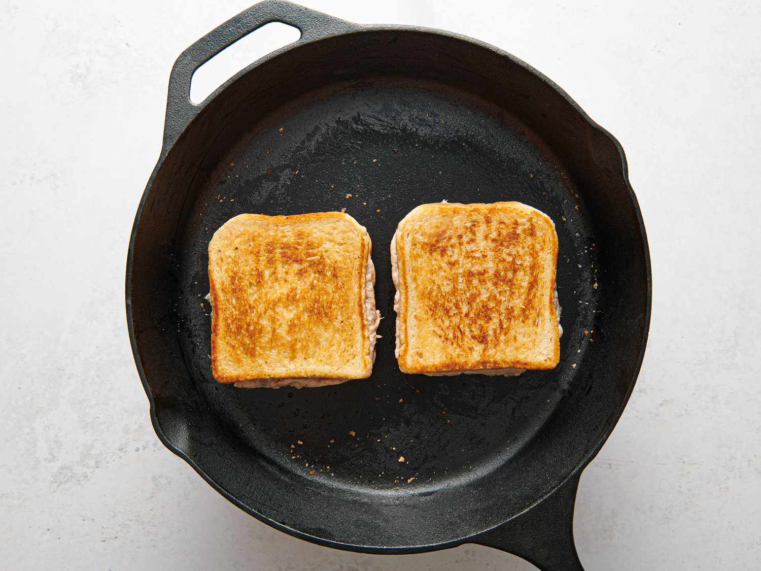 Tuna melt flipped over inside skillet, showing off well toasted side