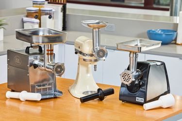 Three meat grinders on a kitchen countertop.