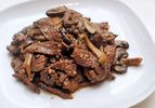 A white plate with a pile of stir-fried beef and mushrooms.