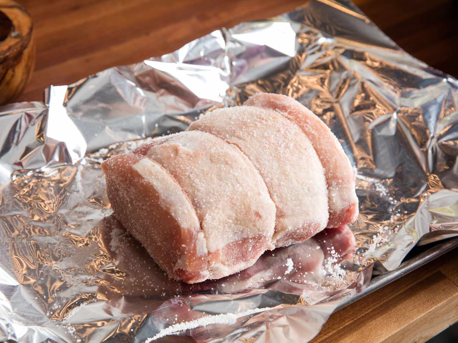 A tied pork loin roast showered with salt for making homemade choucroute garnie.