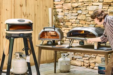 Three outdoor pizza ovens on a patio.