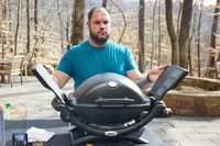 A person closing the wings of a portable gas grill.