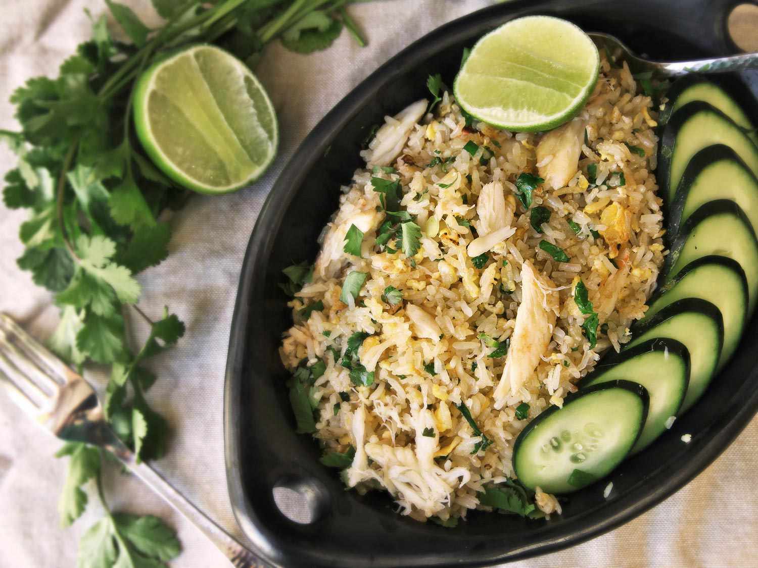 Thai-Style Fried Crab Fried Rice plated with sliced cucumbers and lime