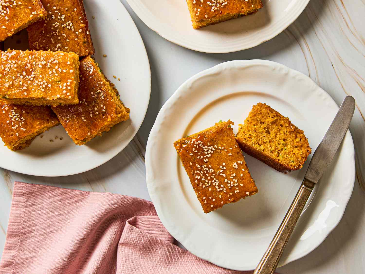 Gochujang scallion cornbread pieces served on plates topped with sesame seeds