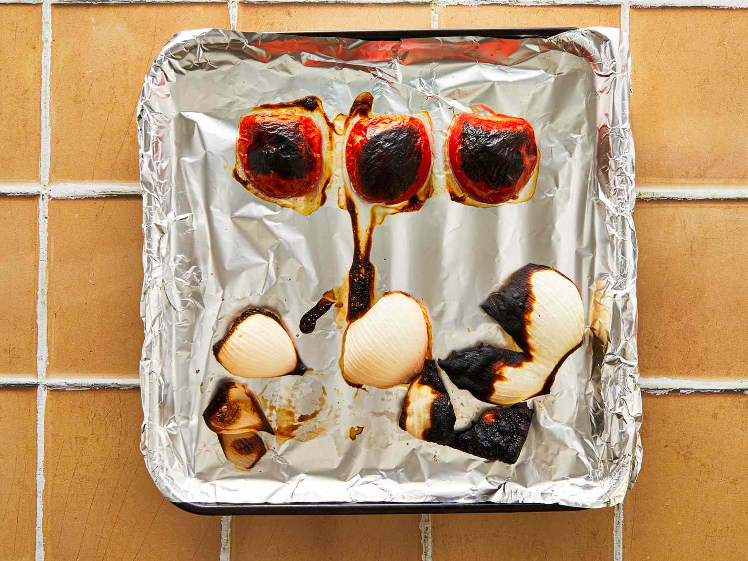 Roasted vegetables including onions and roasted peppers on a foillined tray