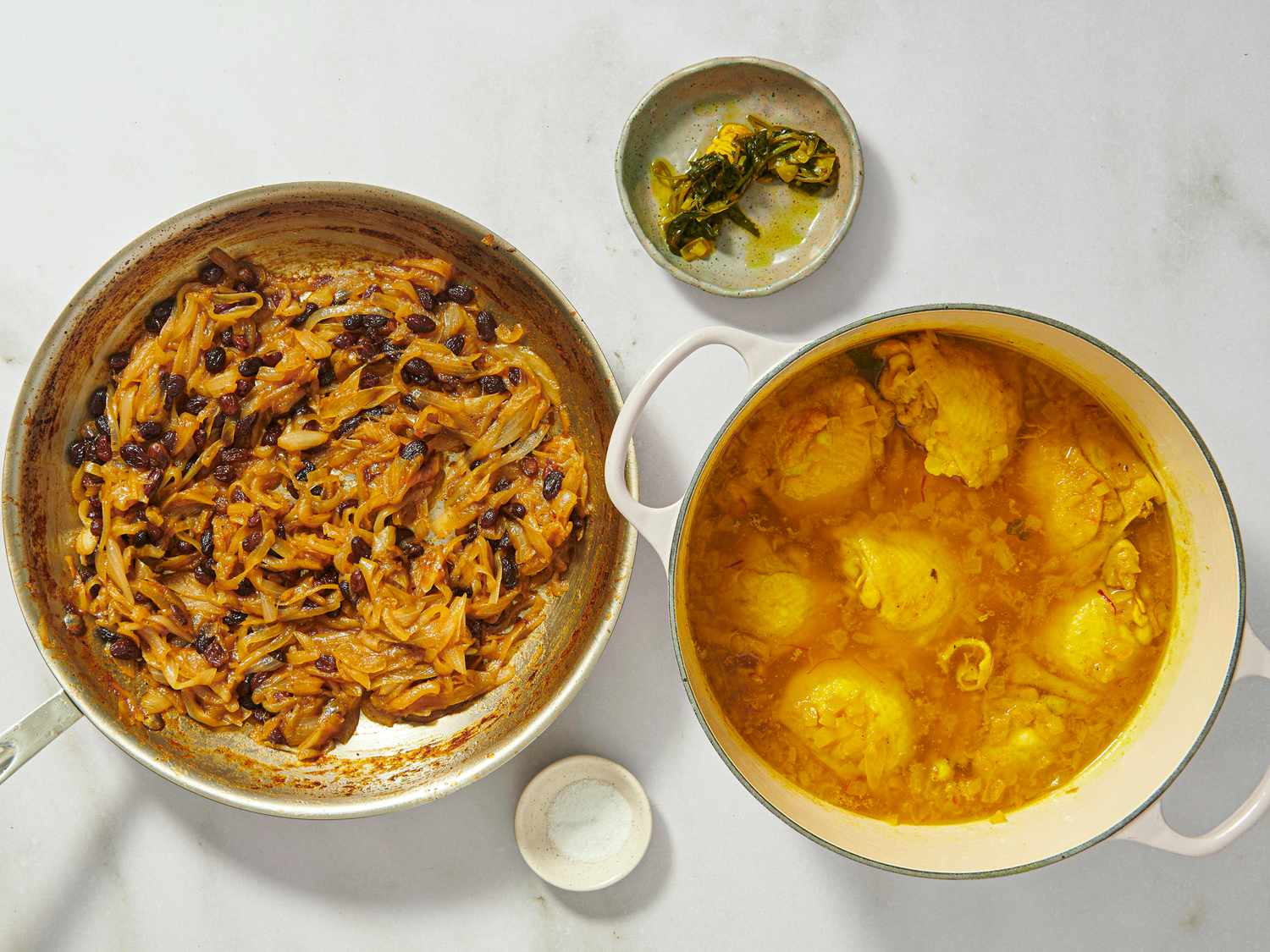pan with onions and raisins next to dutch oven with cooked chicken, and small dish with cooked cilantro