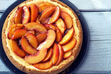 Overhead view of a Bourbon-Roasted Peach Cheesecake, set on a wooden surface.