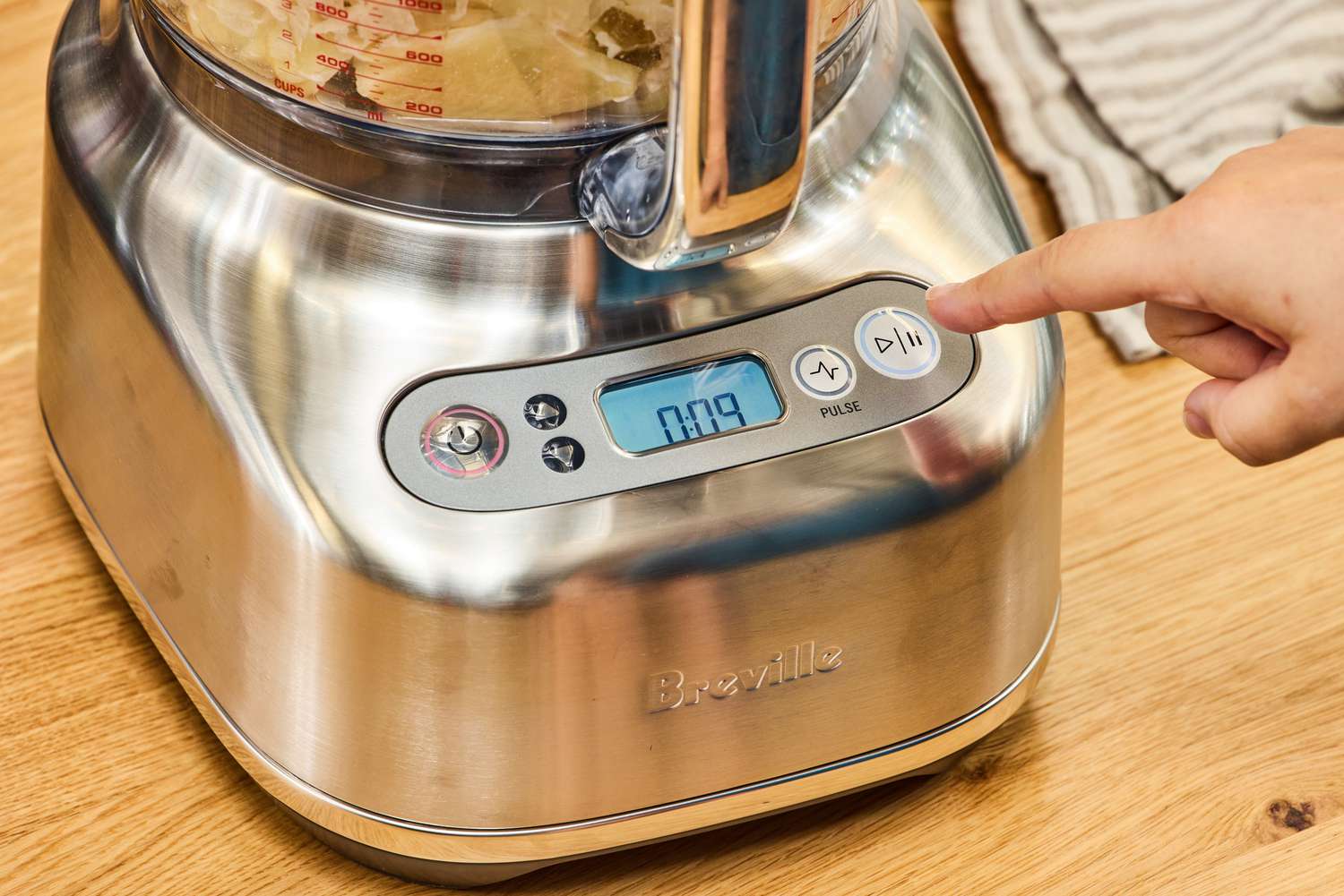 A person presses a button on the Breville BFP838BSS1BNA1 16-Cup Paradice Food Processor