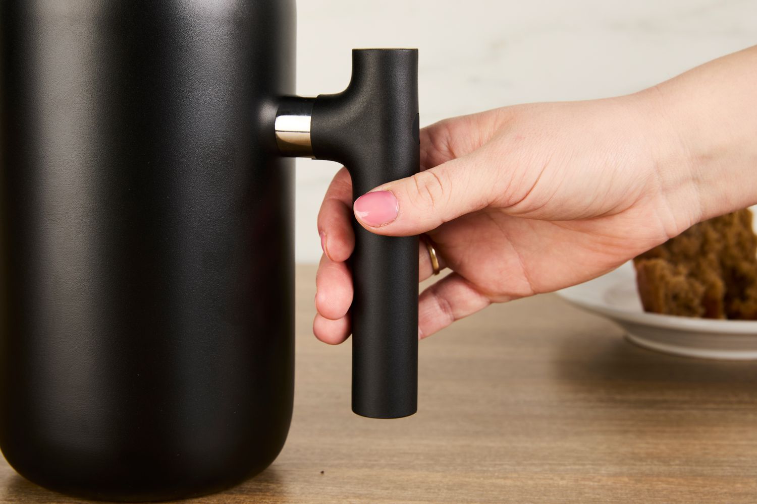 A person grabbing the handle of the Fellow gooseneck kettle.