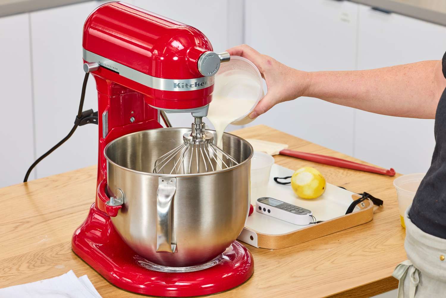 A person pours cream into the KitchenAid 7 Quart Bowl Lift Stand Mixer