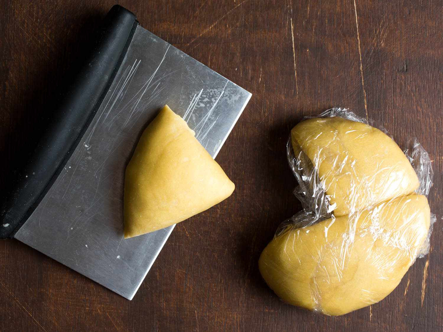 A bench scraper with a cut out piece of pasta dough. 