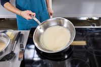A person flips a crepe in the Made In 12-Inch Stainless Steel Skillet
