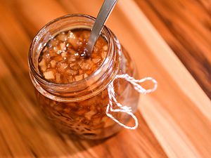 Open jar of pear and ginger preserves with a spoon in it
