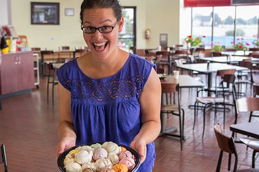 A woman holding a round plate filled with scoops of different flavors of ice cream. The woman has an ecstatic smile on her face.