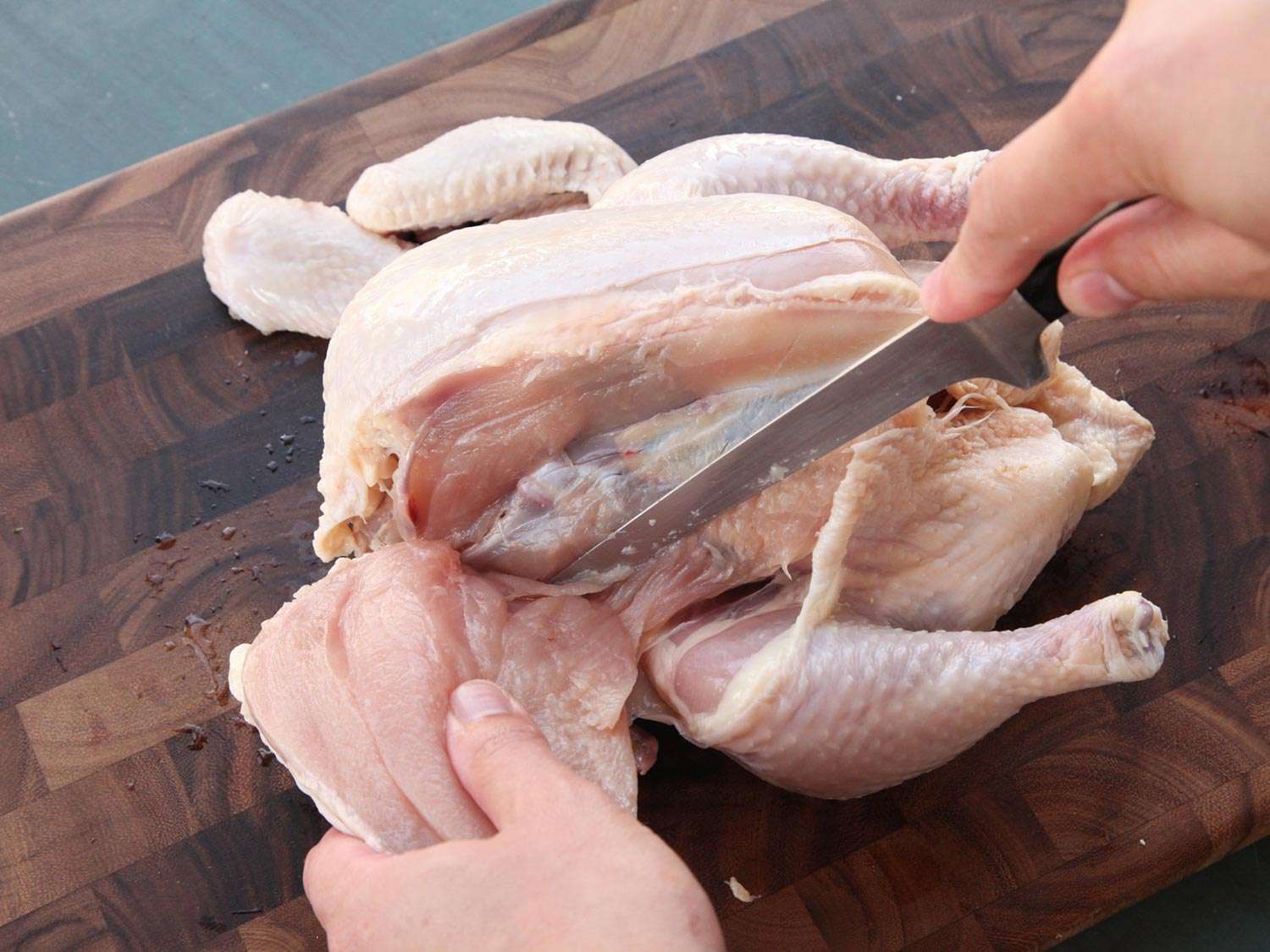 A whole chicken breast being removed from a chicken.