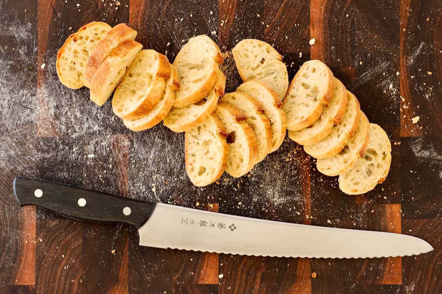Sliced bread on a wooden cutting board with the Tojiro F-687 Hand Made Bread Knife