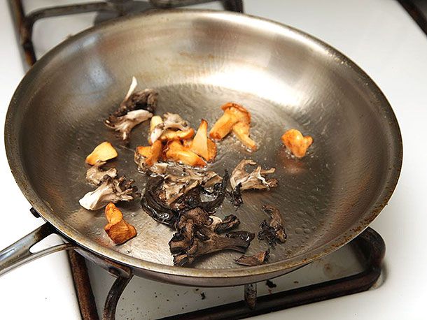 Mushrooms are sautéed in a skillet.