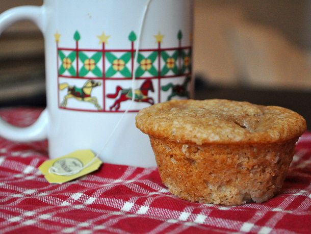 Closeup of an apple buttermilk muffin set next to a mug of tea.