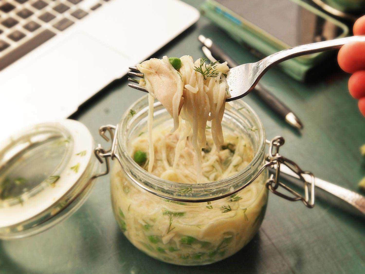 A fork lifts noodles from the jar.