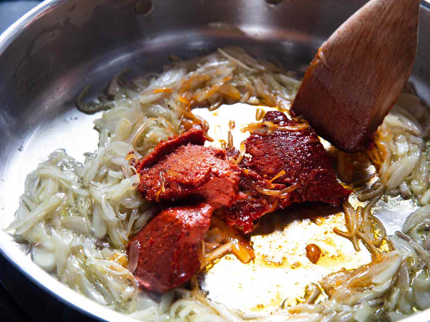 Stirring 'nduja into a pan of white onions.