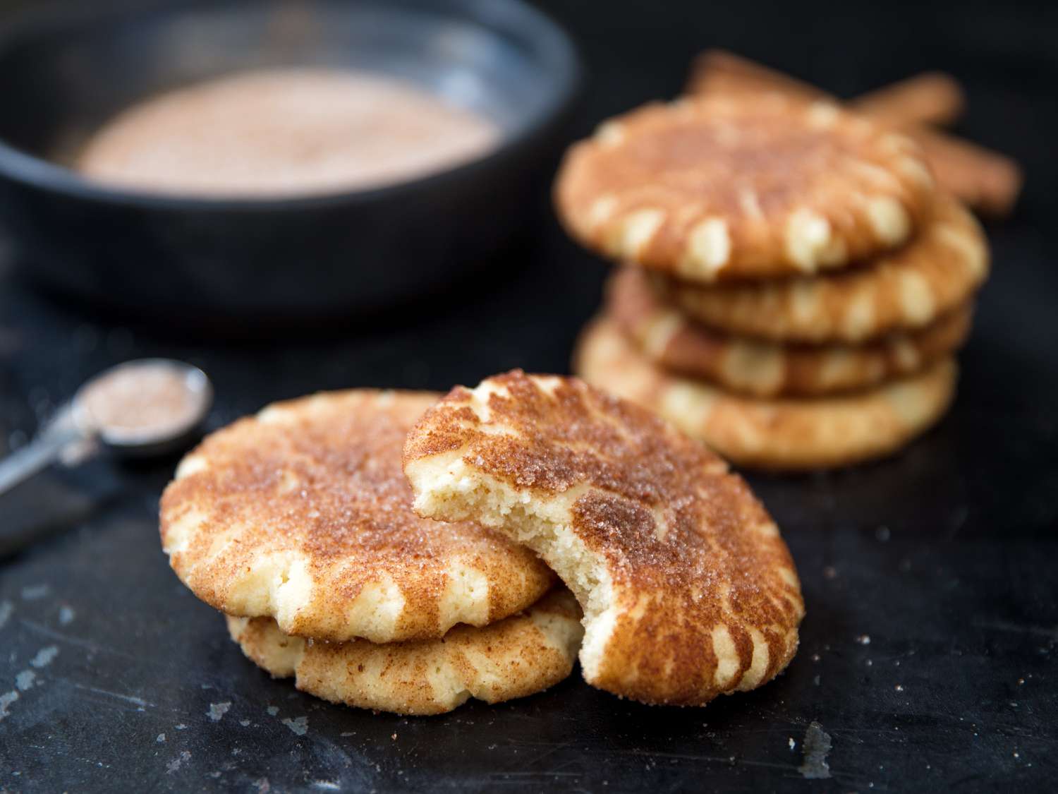 Closeup of stacked new-fashioned snickerdoodle cookies. The top cookie has a bite missing.