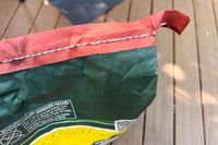 A closeup of a bags stitched top edge with text and warning label visible