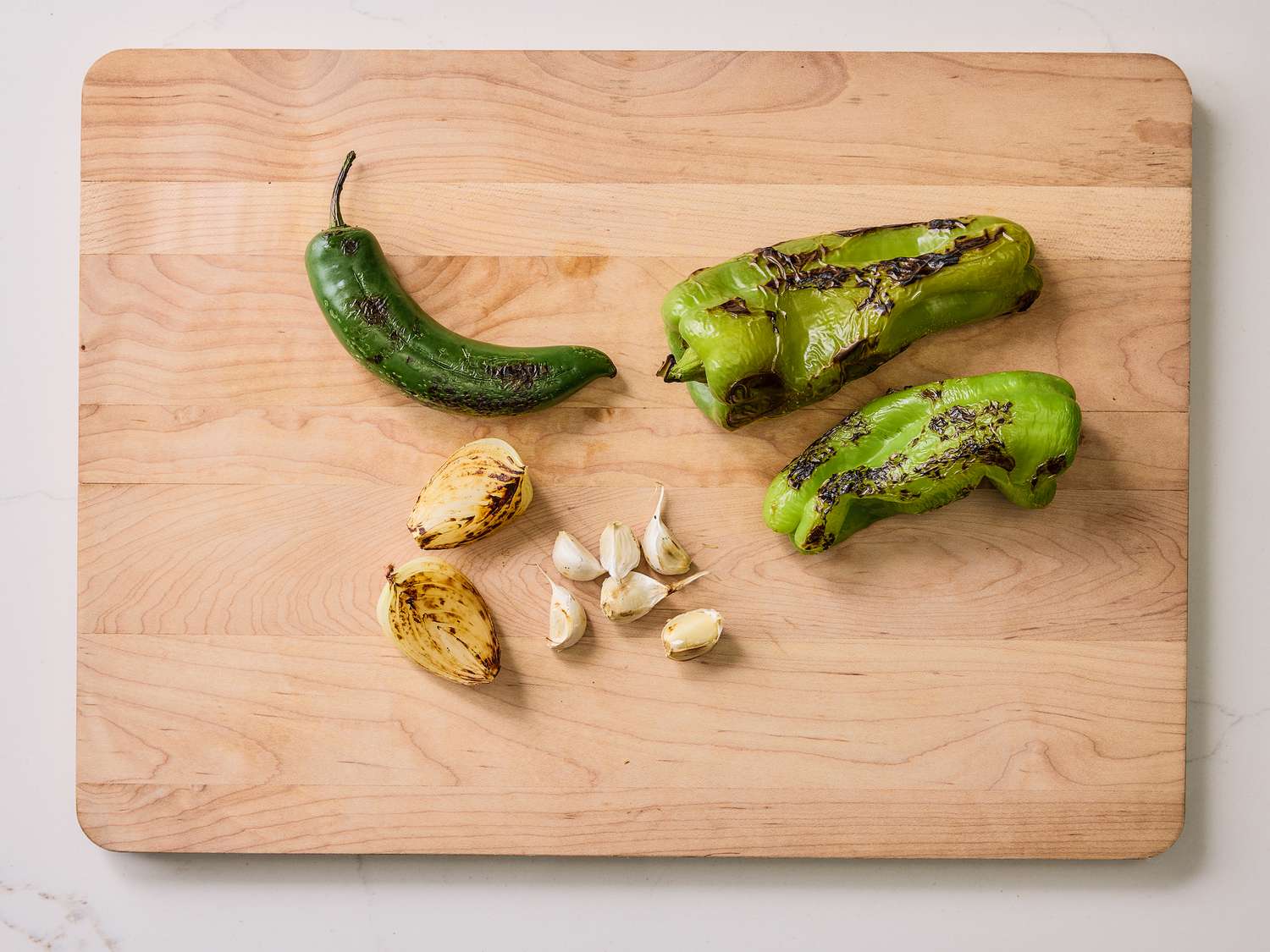 Charred and roasted pepers, onion and garlic on a wooden board 