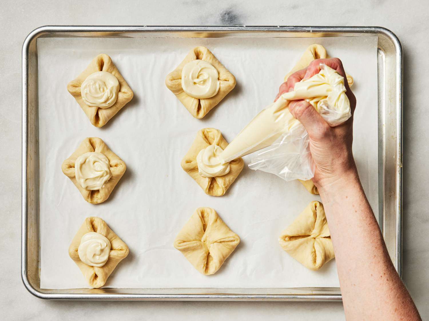 Overhead view of piping icing onto pastry squares