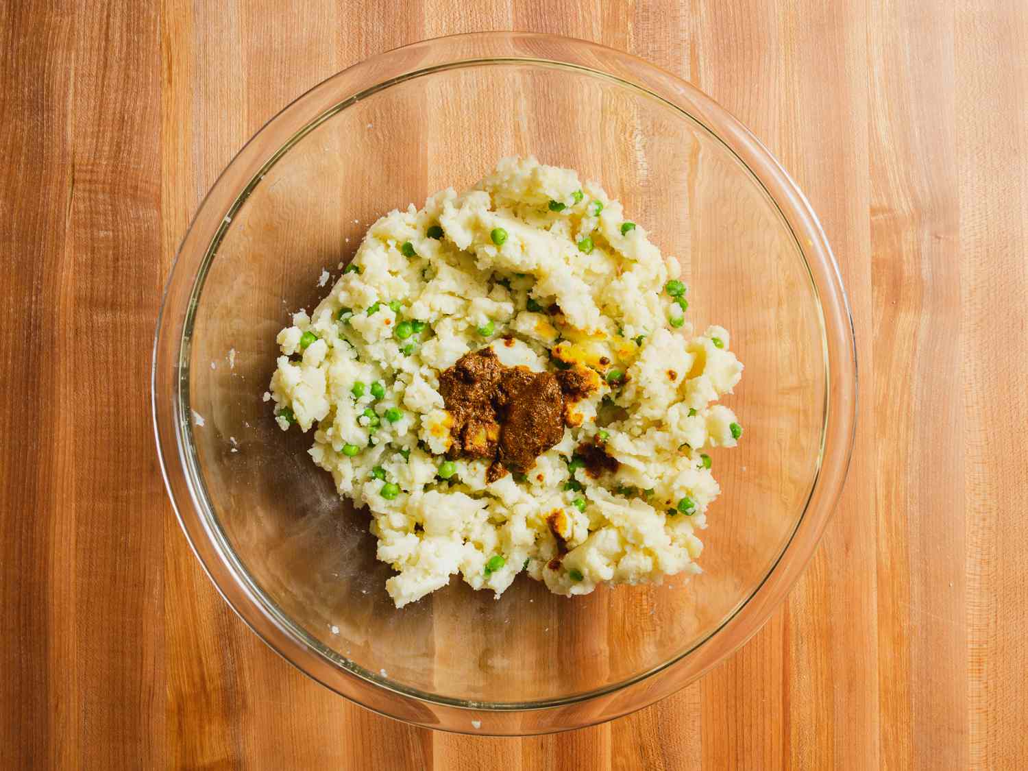 Potato and pea mixture with bloomed spices poured over the top in a bowl