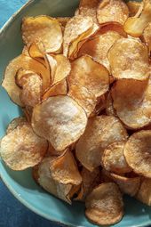 A blue ceramic bowl of potato chips on a blue background.