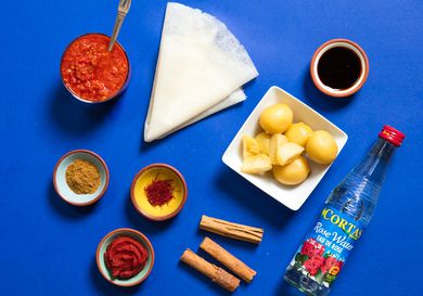 A collection of ingredients used in Moroccan cooking, including preserved lemon, rose water, cinnamon, saffron, Ras el Hanout, harissa, and a sheet of warqa pastry 