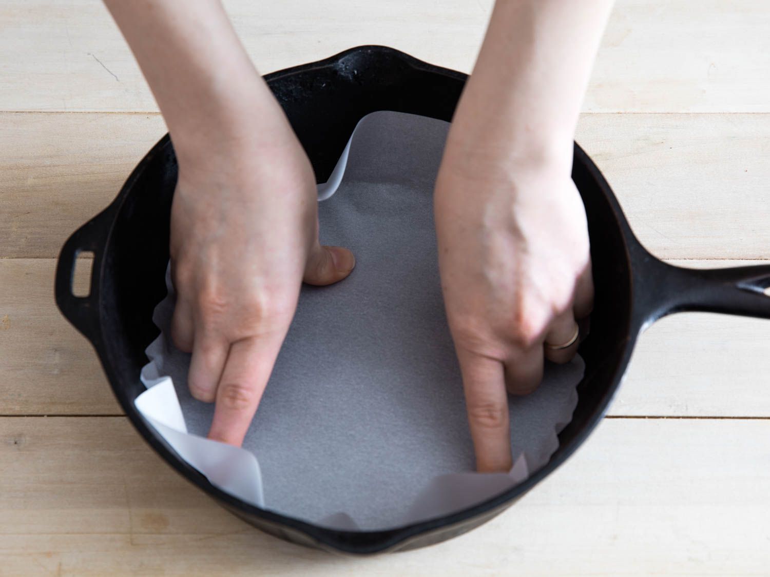Fitting parchment into bottom of cast-iron skillet for soda bread