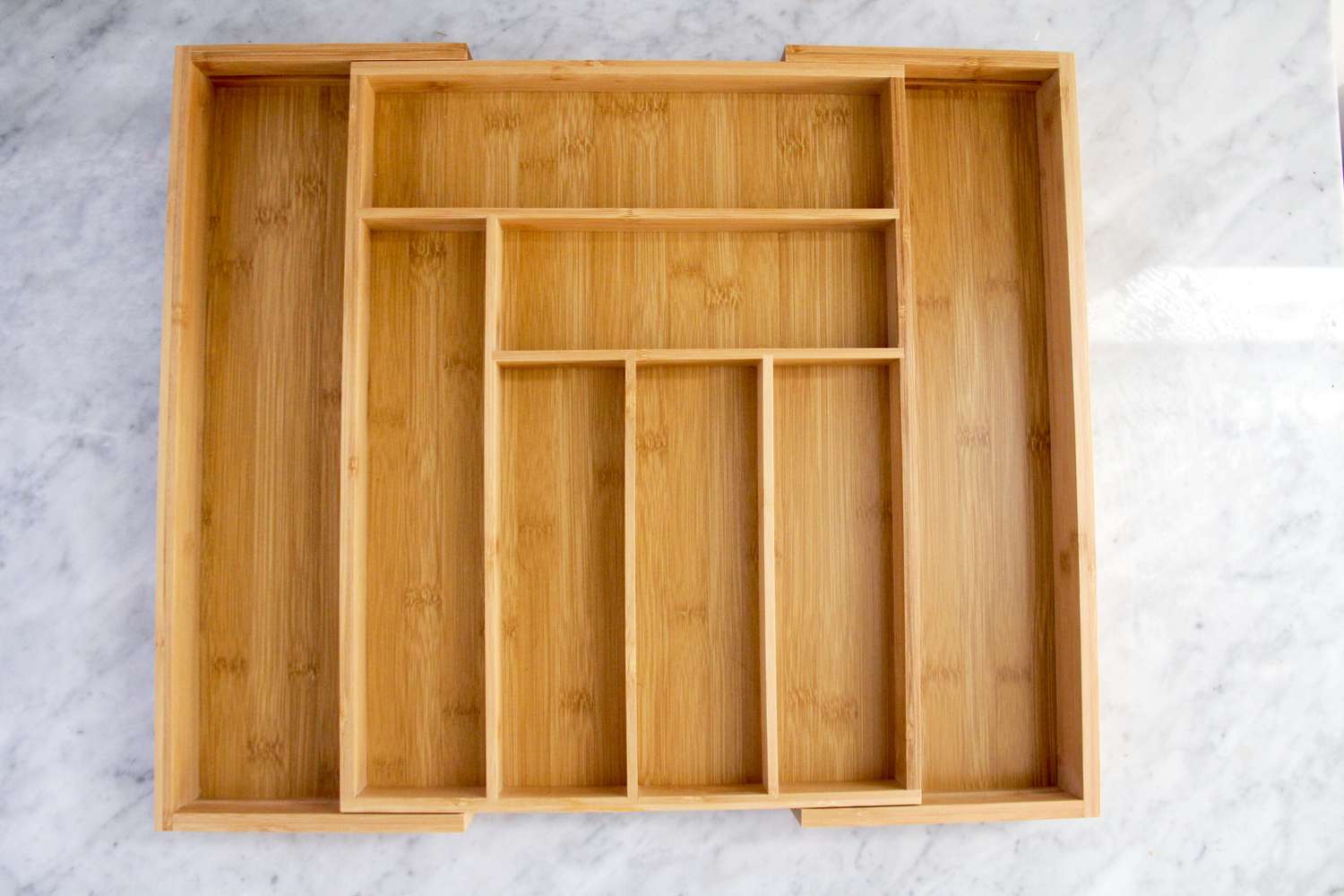 A wooden drawer organizer on a marble countertop.