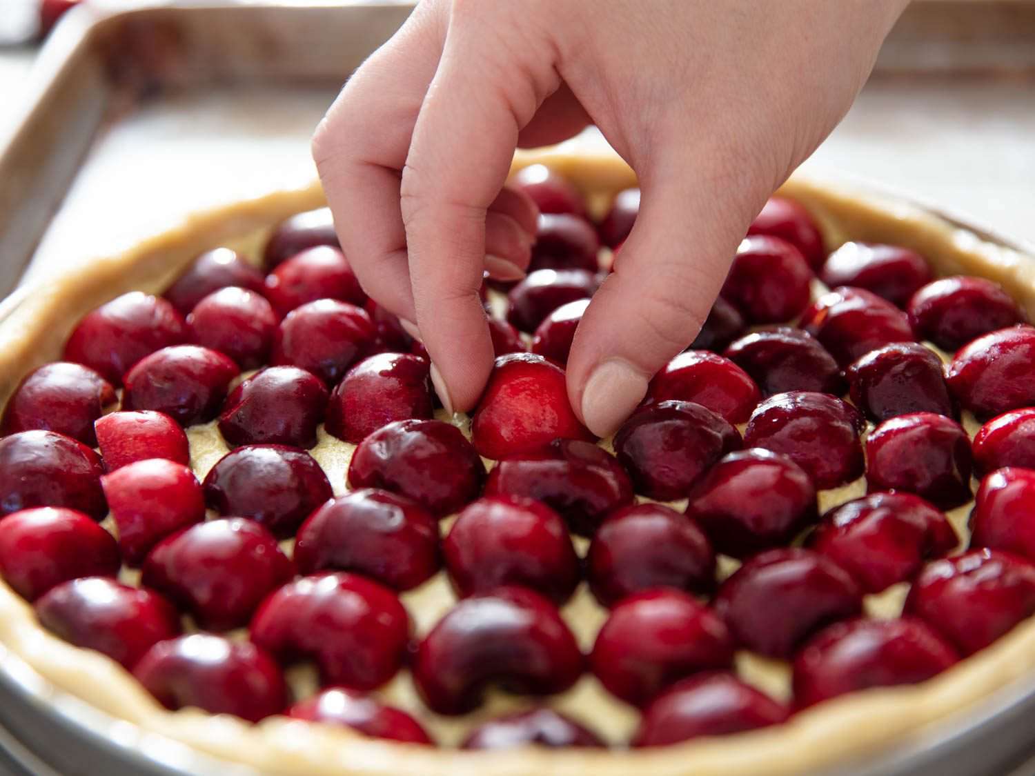 placing the last cherry in the center of the tart