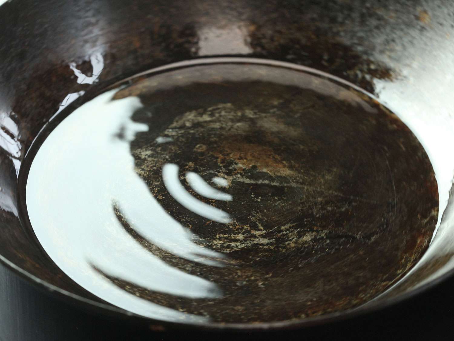 Layer of vegetable oil in a carbon steel skillet being heated until it shimmers before searing salmon.