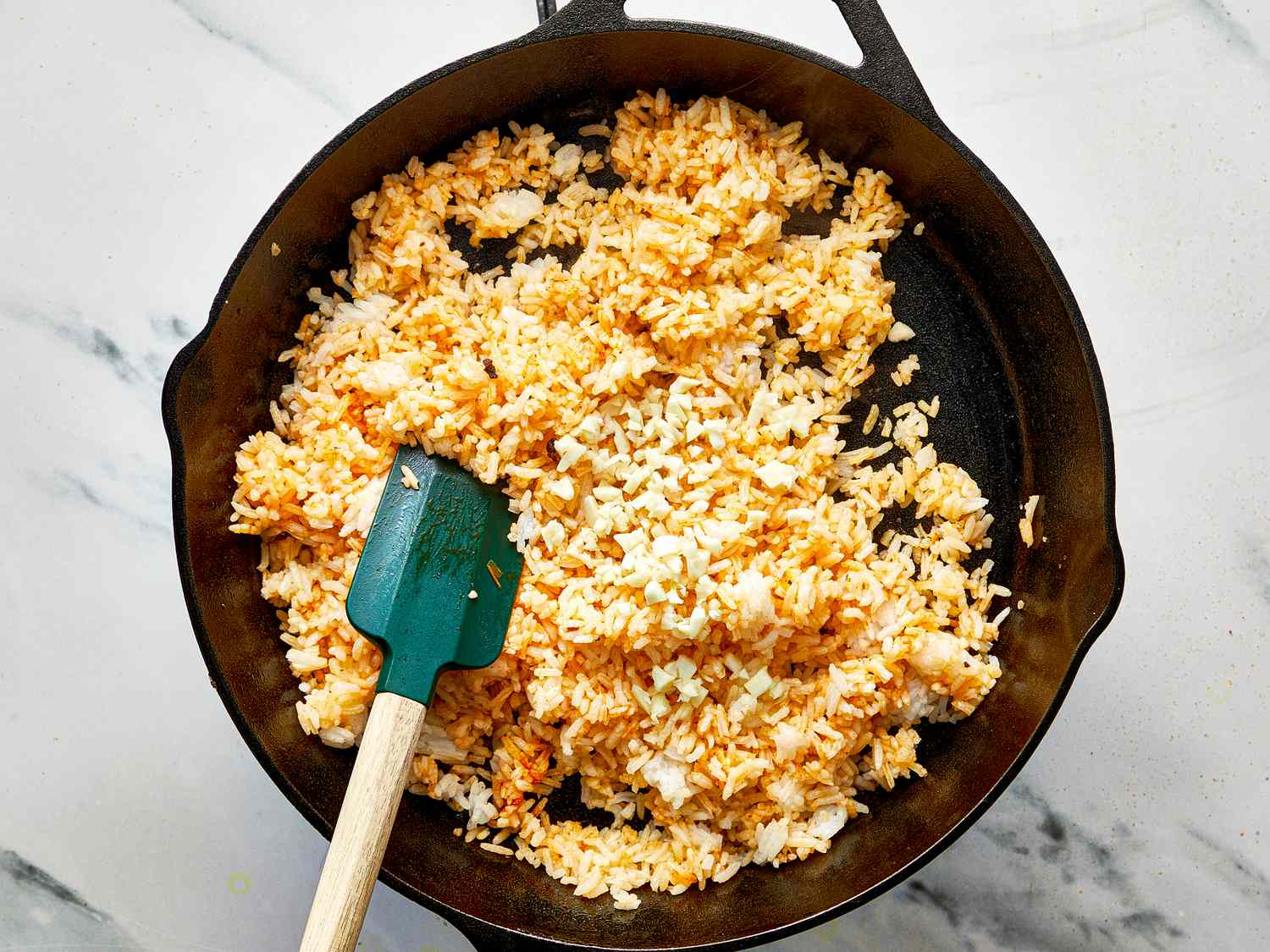 Cooking fried rice in a skillet with a spatula